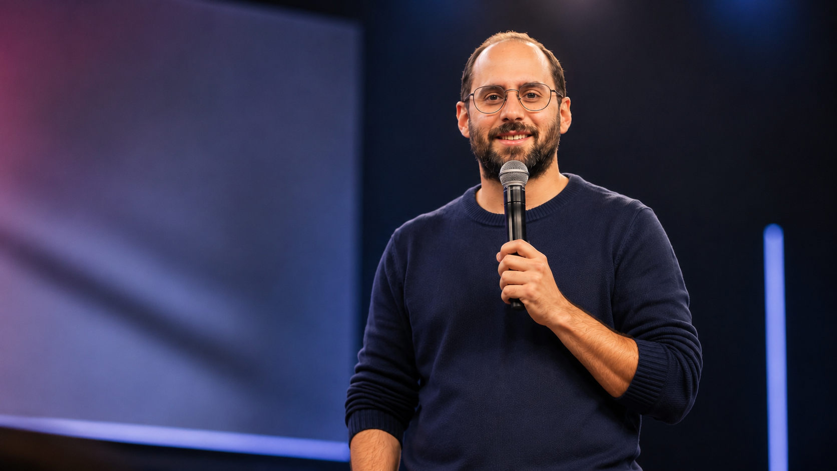 Luis Guimarães no palco, falando ao microfone durante uma palestra
