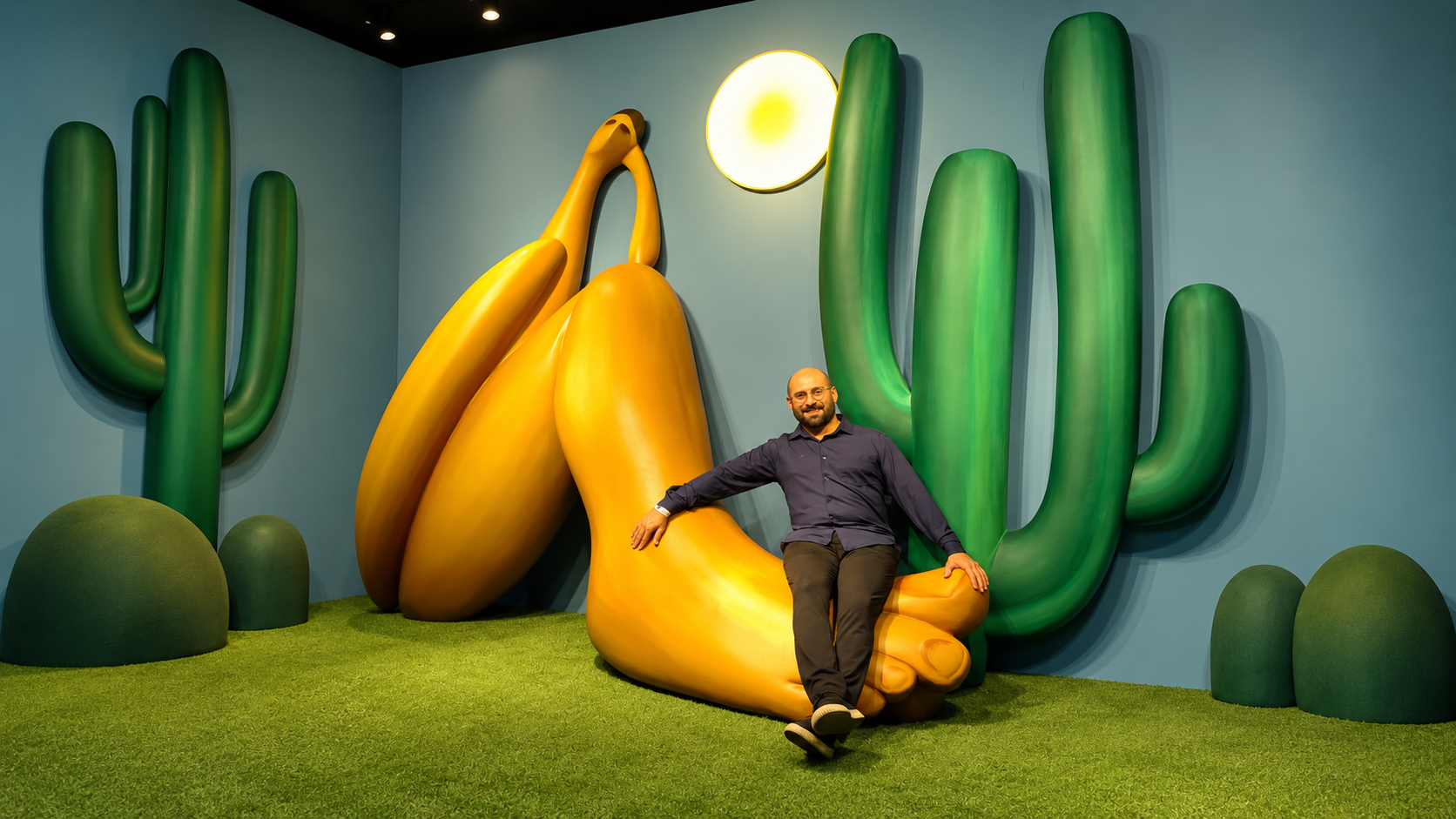 Luis Guimarães sentado na escultura do Abaporu na pré-exibição da exposição O Brasil de Tarsila
